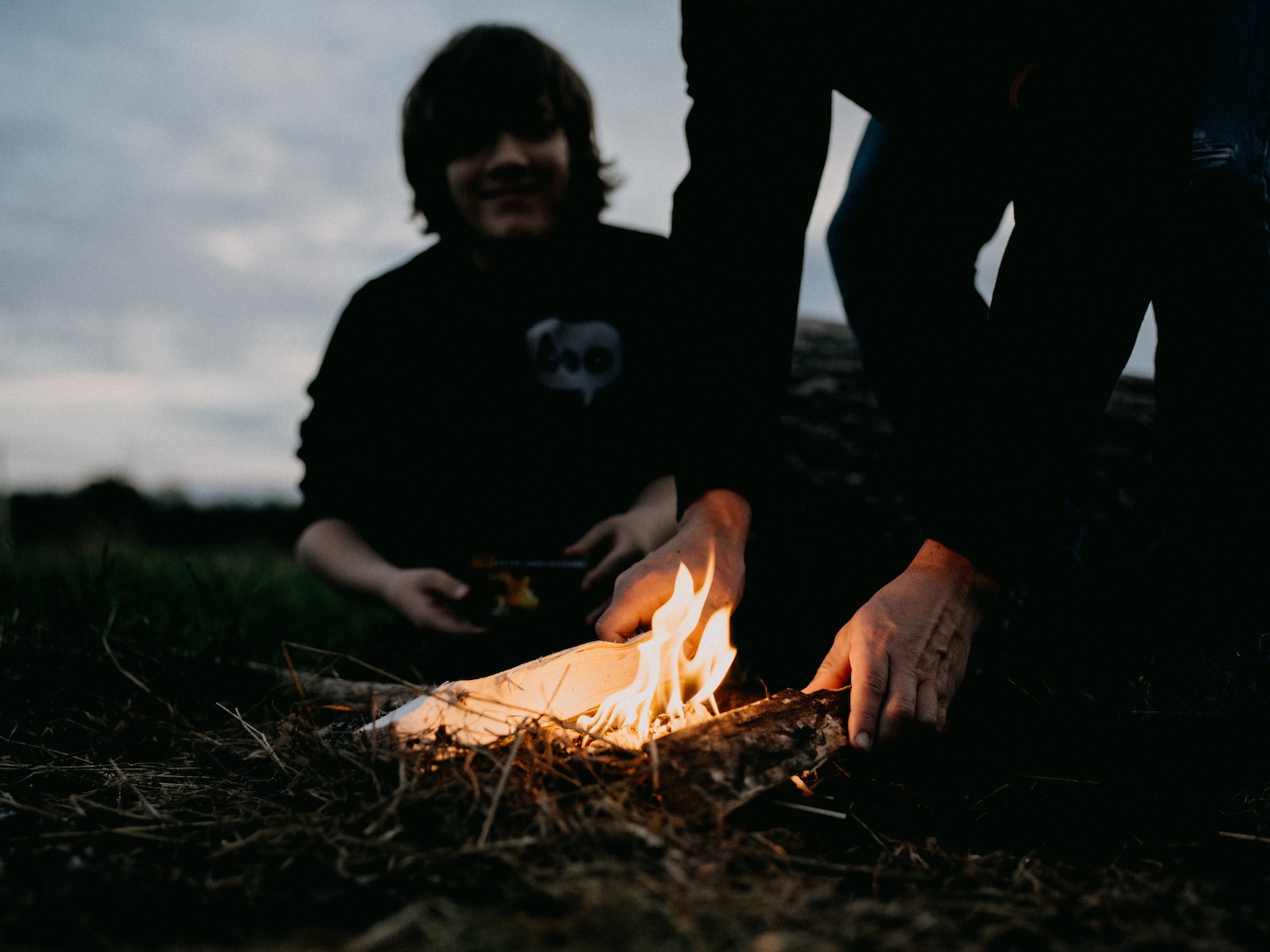 a person sitting on the ground next to a fire